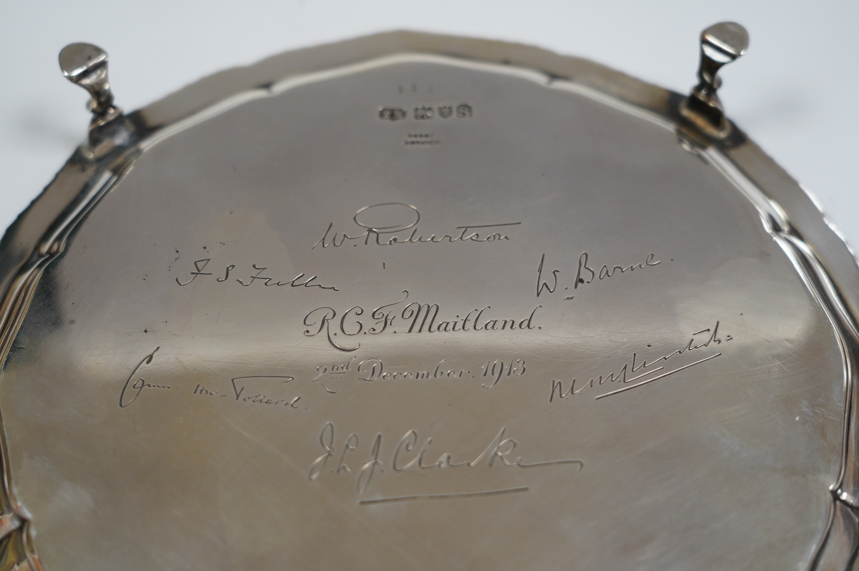 A George V silver shaped circular waiter, with engraved signatures, by Theodore Rossi, London, 1913, on four hoof feet, 203cm, 13.6oz. Condition - fair